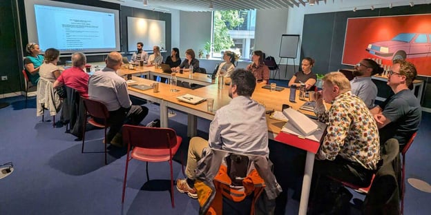 Group of colleagues sitting around a meeting room table following a presentation