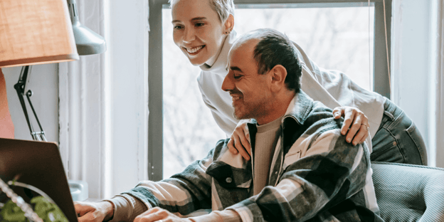 Woman leaning over man who is working from home