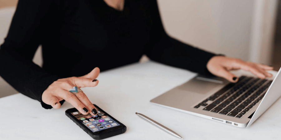 Woman using her phone next to a laptop